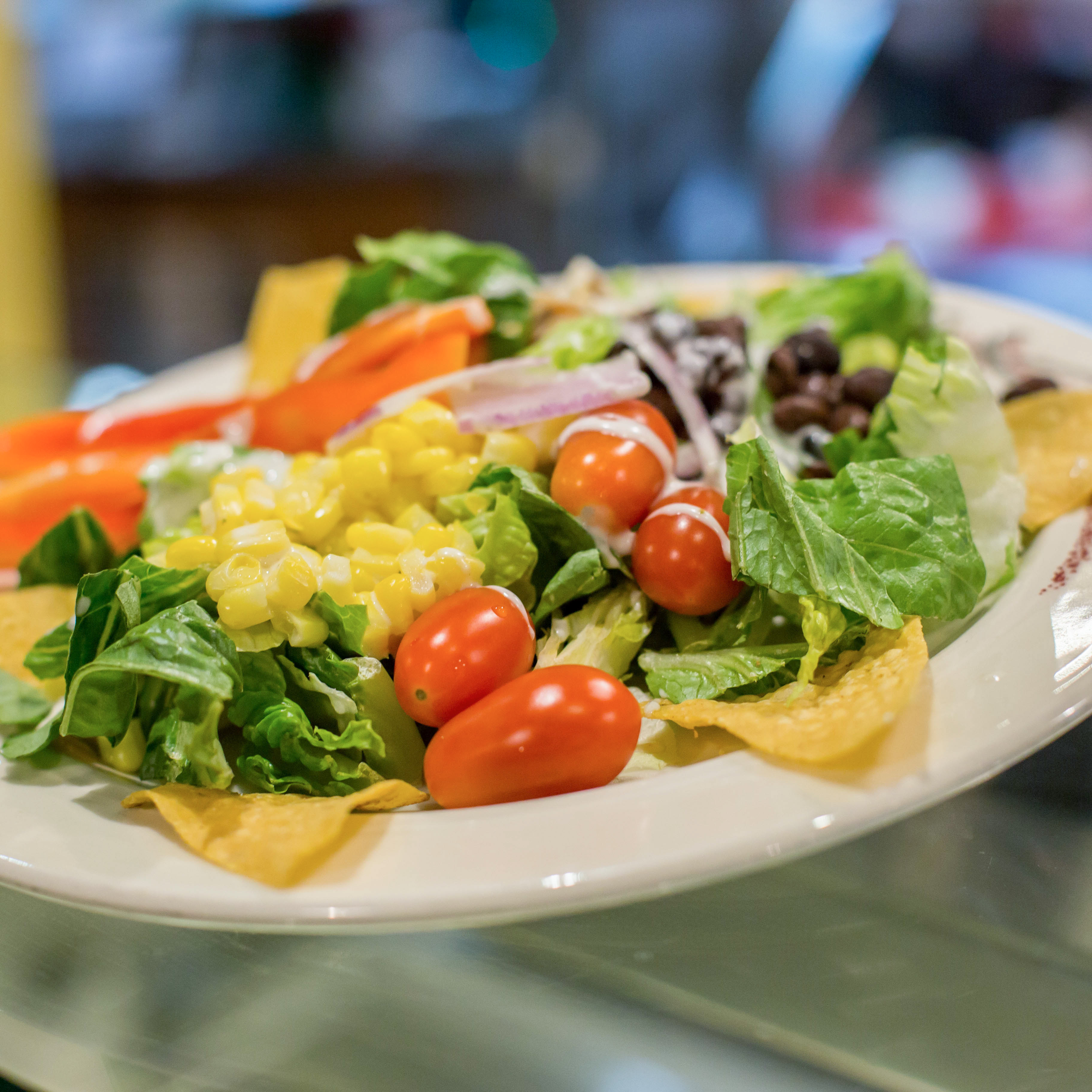A salad with tomatoes, corn, and lettuce.
